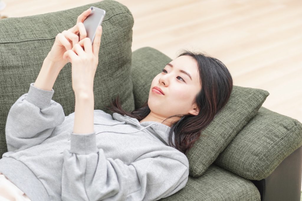 女性がスマホを触っている。