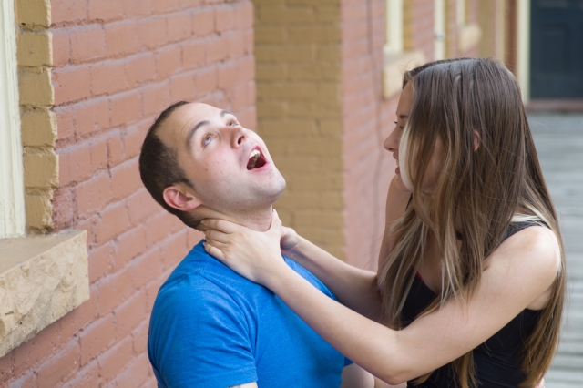 女性が男性の首を絞めている